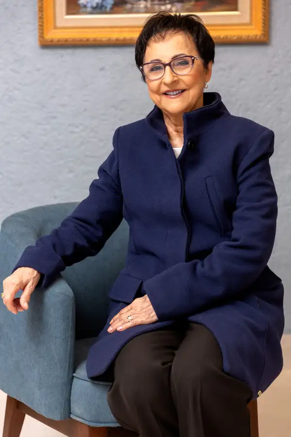 Dra. Neusa Dorigon sentada em uma poltrona, sorrindo